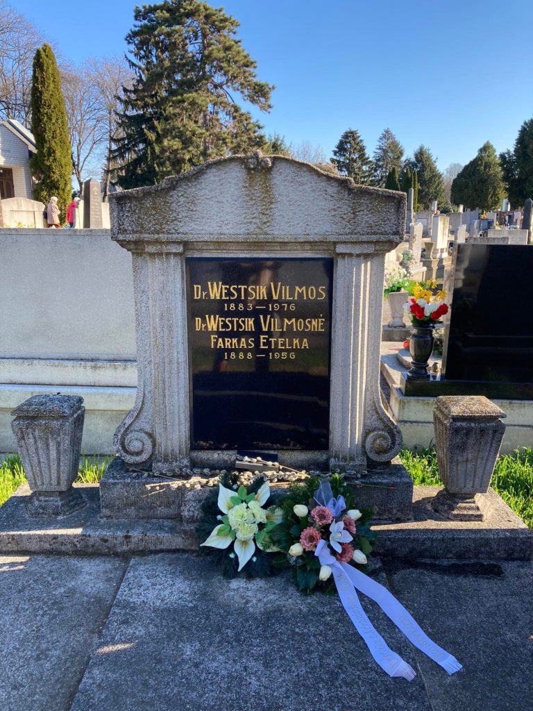 Díszes sírjelet dr. westsik vilmos és mások, vésett névvel és dátummal, friss virágokkal díszítve, napfényes temetőben.