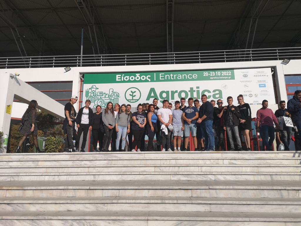 A 2022. október 20. és 23. között megrendezett Agrotica rendezvény bejárata előtti lépcsőn áll egy nagy csoport. A csoport a kamera felé néz. A háttérben egy szalaghirdetés látható az esemény nevével és dátumaival.