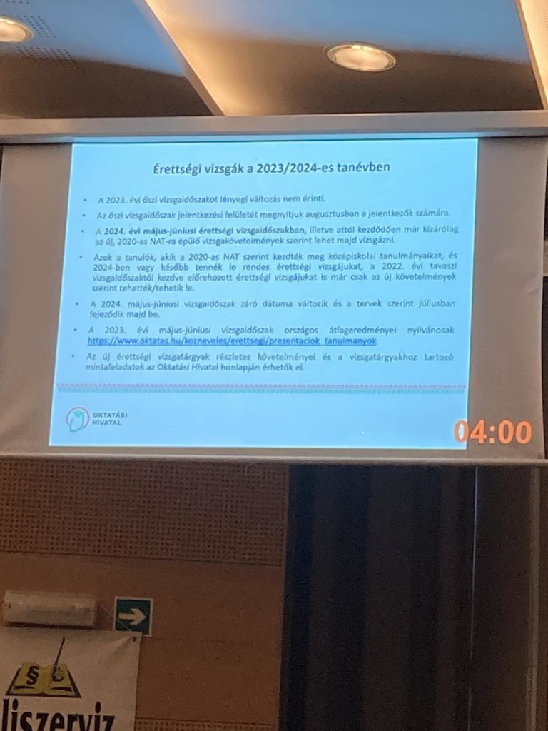 A 2023/2024-es tanév érettségi vizsgáiról magyar nyelvű prezentációs dia vetítésre kerül egy képernyőre. A háttérben a mennyezet egy része és a bal alsó sarokban egy tábla egy része látható. A képernyőn az idő 04:00.