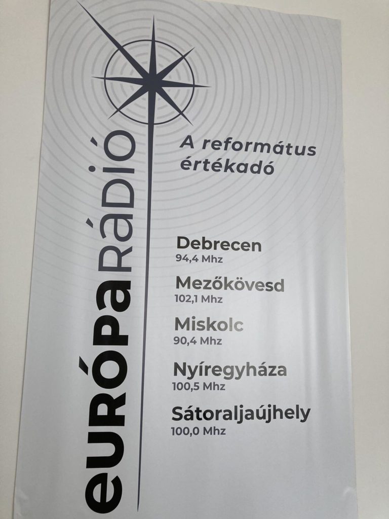 Az „Európa Rádió” plakátja „A református értékadó” felirattal. Különböző városok rádiófrekvenciáit sorolja fel, köztük Debrecen (94,4 MHz), Mezőkövesd (102,1 MHz), Miskolc (90,4 MHz), Nyíregyháza (100,5 MHz) és Sátoraljaújhely (100,0 MHz).
